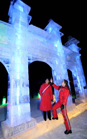 A tourist (R) takes pictures of the ice sculpture with her mobile phone as her friend looks on during the 4th Ice, Snow, Cultural and Tourism Festival in Barkol Kazak Autonomous County, northwest China's Xinjiang Uygur Augonomous Region, Jan. 5, 2009. The 4th Barkol Ice, Snow, Cultural and Tourism Festival was opened on Jan. 5, displaying more than 100 ice or snow sculptures and holding ice and snow sports games to promote the local herdsmen's traditons near Xinjiang's Hami city. (Xinhua/Zhu Zhenghua)
