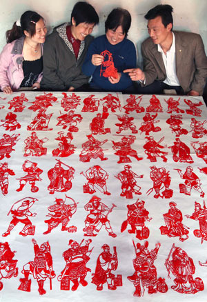 Folk artist Wang Zhenzhu (2nd R) shares pleasure with neighbors in appreciating her paper-cuttings of 108 generals of Chinese classic novel