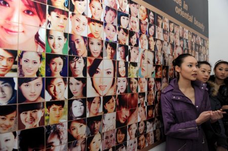 Model candidates rest in front of posters with faces of successful models and entertainers before taking part in an interview in Qingdao, a port city in east China's Shandong Province, Dec. 12, 2009. More and more Chinese yongsters choose show business to begin their professional career. (Xinhua/Li Ziheng)