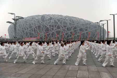 People practise Taiji in front of the National Stadium, also known as the Bird's Nest in Beijing, capital of China, August 8, 2009.(Xinhua File Photo)