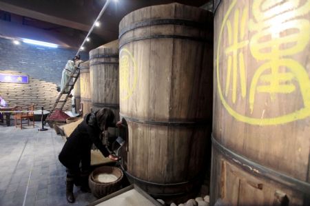 A visitor experiences extracting the grain from the imperial grain-storing cask on display inside the Imperial Granary Museum of Ming Dynasty of Nanxingcang Barn, which has been opened to public visitors, in downtown of Beijing, Jan. 16, 2010. Affluent exhibits reenacting the history of grains transport through the Grand Canal and the imperial barns storage are accessible to visitors, who can also experience the quern of stone mill some 600 years ago. (Xinhua/Luo Wei)