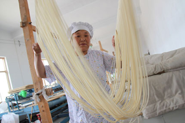 A woman makes hollow noodles on June 9, 2010, in Tangyin County of central China's Henan Province. There is a tradition of making hollow noodles by hand in the county's Yigou Town, where some craftsmen can make a dough into hollow threads as long as 200 meters by repeatedly stretching and folding it. (Photo: Shanghaidaily.com)
