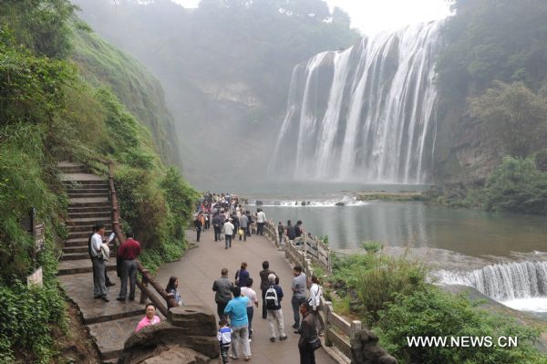 Tourists pose for photos in front of Huangguoshu Waterfall in southwest China's Guizhou Province, May 15, 2011. Due to the continuous heavy rainfall, the Huangguoshu Waterfall has entered into the high flow period ahead of time, closely followed by its tourist season. (Xinhua/Ou Dongqu)(zxh) 
