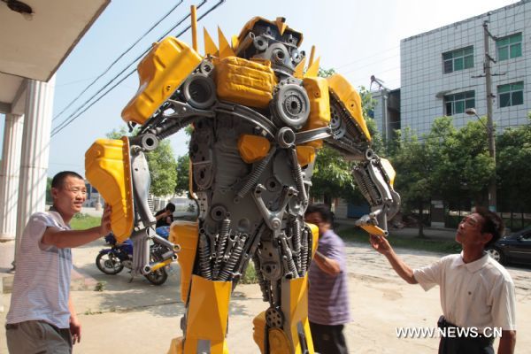 Citizens watch a 'transformer Bumblebee' made by a welder in Zhijiang City, central China's Hubei Province, July 25, 2011. As the film 'Transformers 3' was on show in China recently, welder Xiong Wei in Zhijiang made a Bumblebee model out of waste car and motorcycle parts in 12 days. Xiong planned to sell the 2.7-meter-high 'transformer' to a company in Shenzhen for exhibition. (Xinhua/Liu Weidong) (llp) 