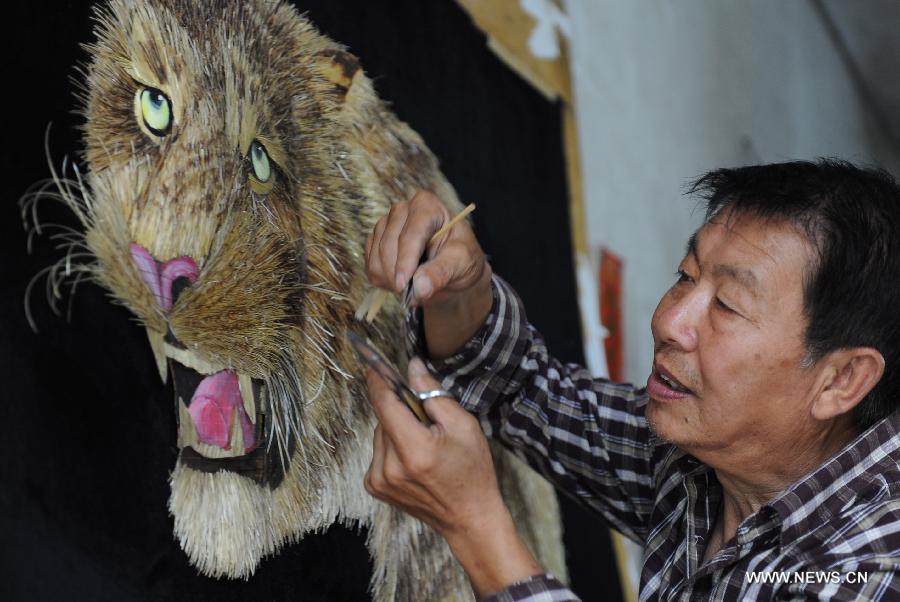 Folk artist Kang Xiukui selects straws for making paintings with skills of pyrography and straw painting in Puxian County, north China's Shanxi Province, Aug. 15, 2012