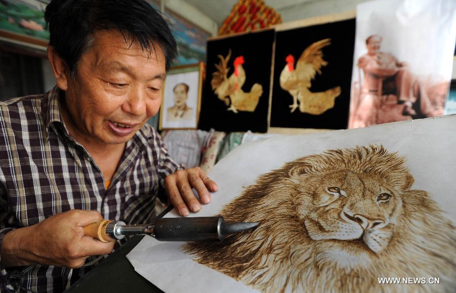 Folk artist Kang Xiukui selects straws for making paintings with skills of pyrography and straw painting in Puxian County, north China's Shanxi Province, Aug. 15, 2012